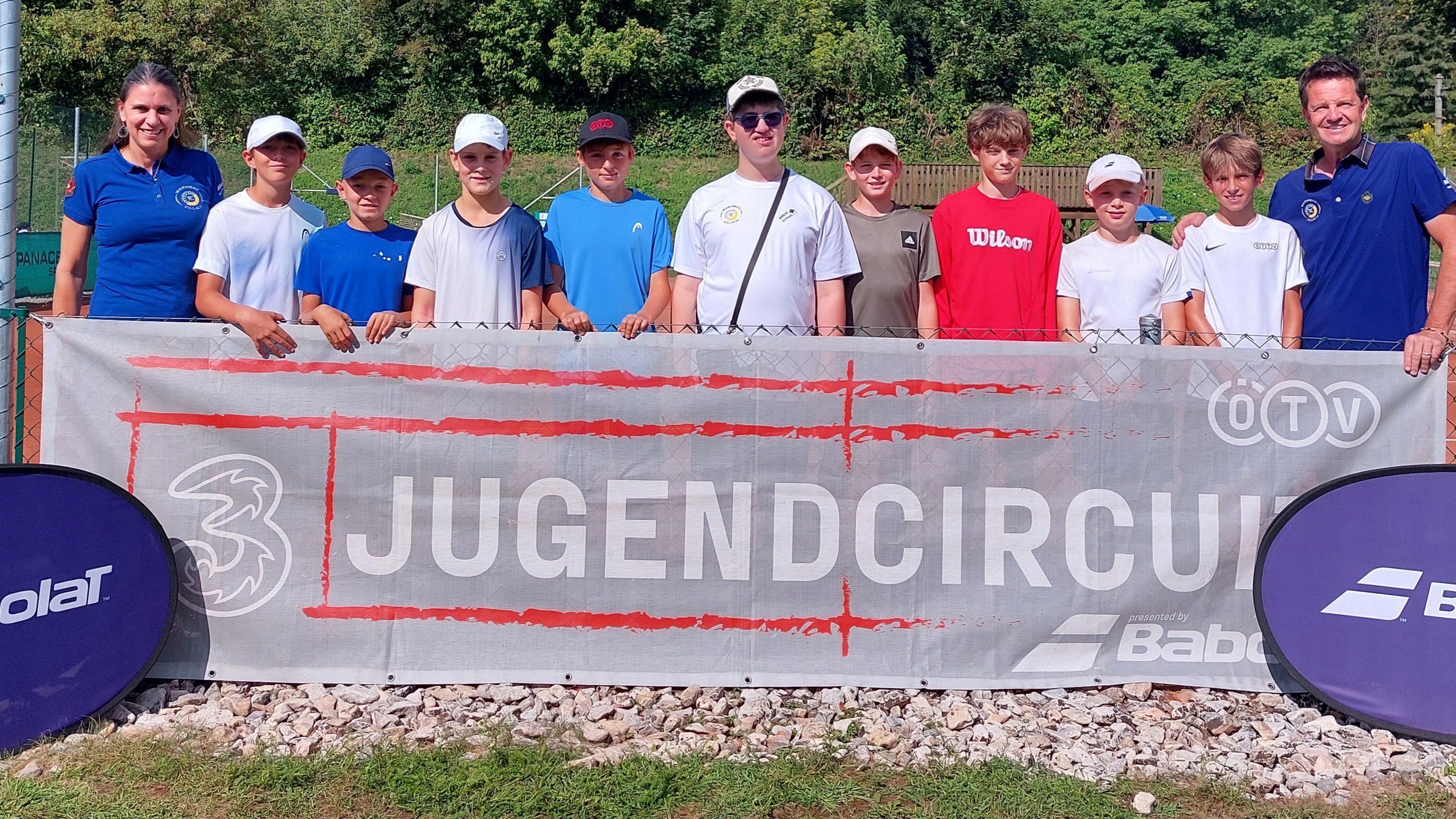 Jugendcircuit-Teilnehmer mit Betreuern vor Banner in Österreich