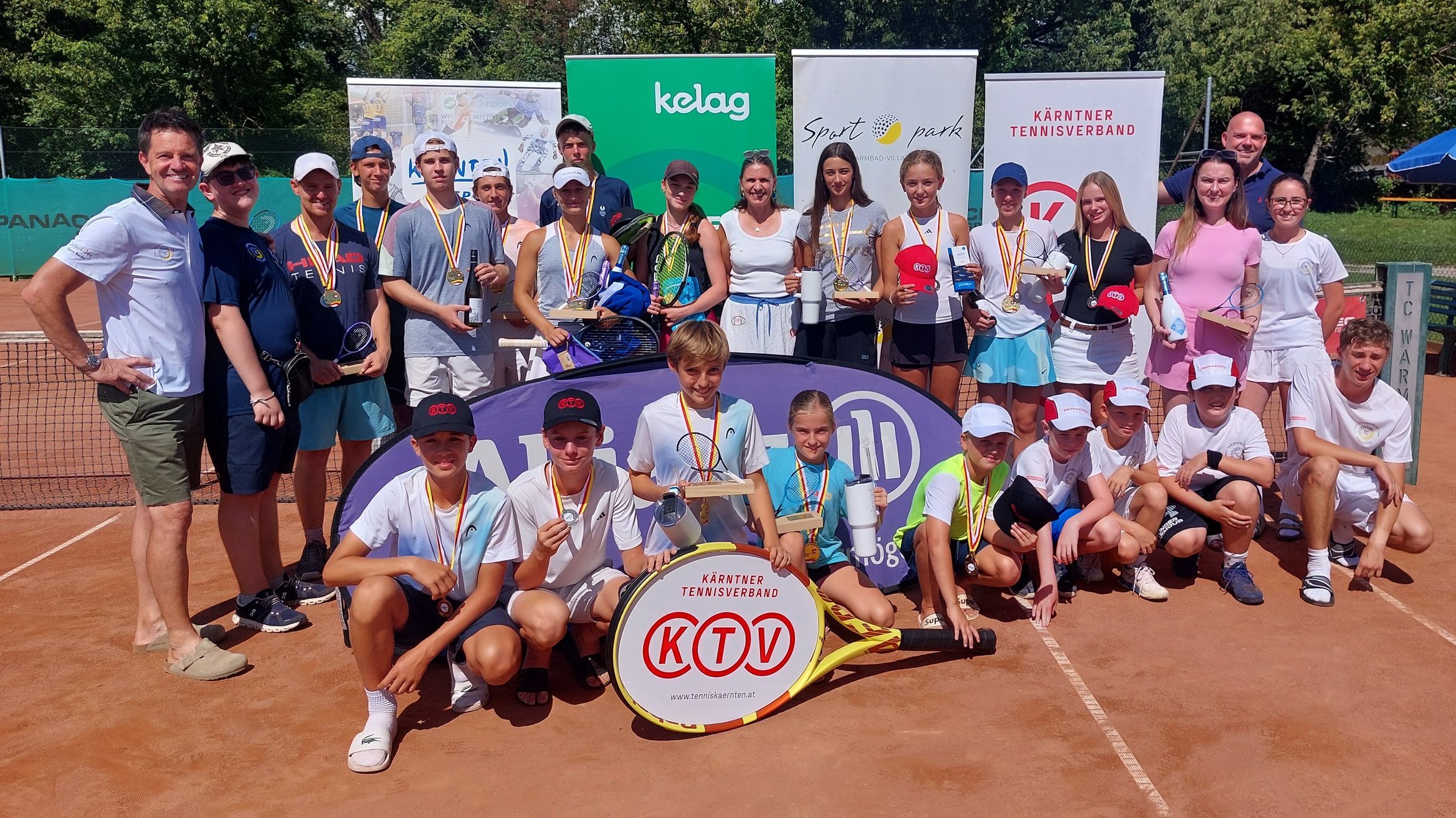 Tennisspieler und Organisatoren mit Medaillen und Pokalen auf einem Tennisplatz in Kärnten
