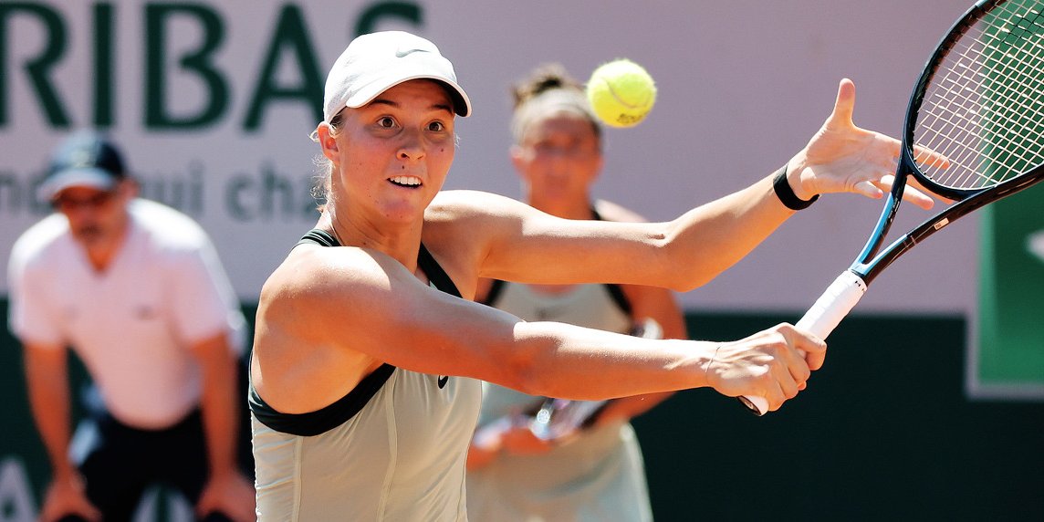 Tennisspielerin schlägt Ball auf Sandplatz, dahinter Schiedsrichter und Gegnerin